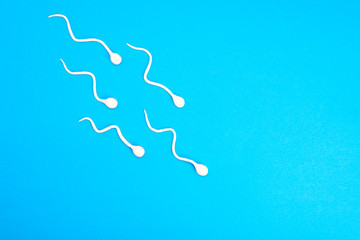Active sperm swim on a blue background. The concept of pregnancy, fertilization of the egg. Top view