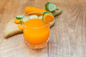 Carrot juice. Healthy food, healthy drink. Orange juice in a glass and next to peeled carrots, sliced cucumber. healthy eating for breakfast. Wood background