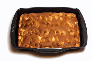 freshly baked ruddy apple pie in a metal rectangular shape. Charlotte pie in baking dish isolated on white.