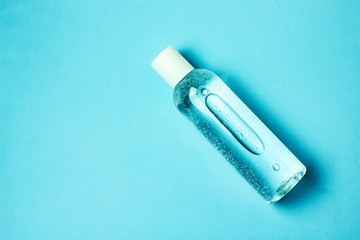 Transparent cosmetic bottle on a blue background, copy space, top view. The concept of skin care, natural cosmetics.
