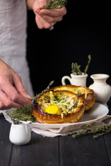 baked bread with ham, greens, cheese and egg on a wooden background