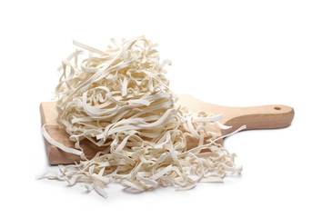 Raw tagliatelle rice pasta noodles on chopping board isolated on white background