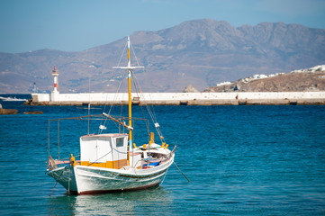 Fototapeta na wymiar Traditional Greek boat moored in a calm Mediterranean harbor in Mykonos, Greece