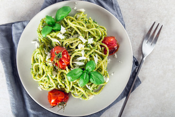 Pasta spaghetti with homemade pesto sauce, roasted tomatoes and fresh basil leaves, vegetarian food