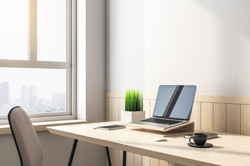 Minimalistic office with laptop with blank screen on table.