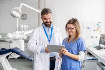 A dentist with dental assistant in modern dental surgery, working.