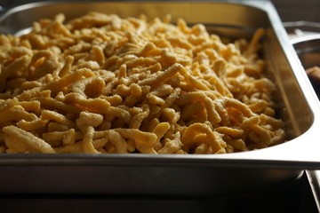 a pile of homemade swabian spaetzle pasta noodles in a castronrom pan container