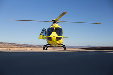 Fototapeta na wymiar Helicóptero Amarillo sobre cielo azul preparado para iniciar vuelo de ala rotatoria 
