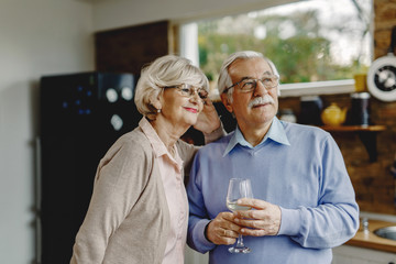 Portrait of happy senior couple day dreaming in the kitchen.