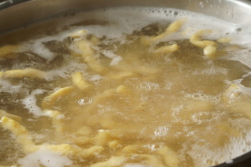a pile of homemade swabian spaetzle pasta noodles cook in a pot in hot water