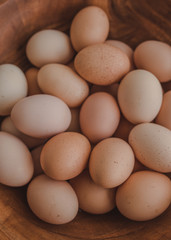 A lot of organic eggs in a large wooden bowl. Chickens eggs from ecologically clean areas. Eggs of different colors. Easter concept. Top view.