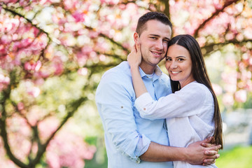 Young couple in love standing outside in spring nature.