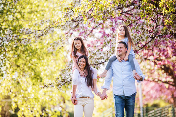 Young parents with small daugthers walking outside in spring nature.