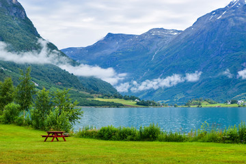 Fototapeta na wymiar Landscape of beautiful Oldevatnet glacial lake and foggy mountains in which there are glaciers of Jostedalsbreen National Park. Norway.