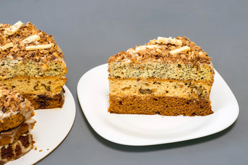 Chocolate cake with a separate piece on a white plate on a gray background