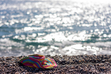 Fototapeta na wymiar Colorful beach hat on a pabbles beach