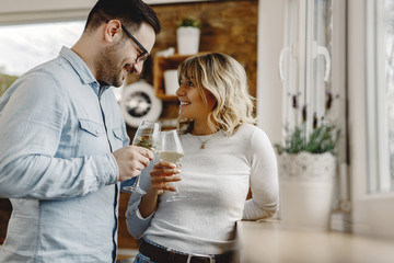 Happy couple toasting with wine by the window.