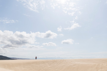 desert landscape man in the distance on a sand dune a windy and sunny day, blue sky with some white clouds