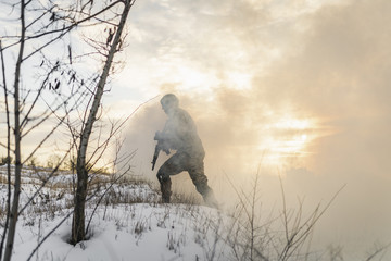Soldier army man running through the smoke and explosions sun backlight and smoke background. modern warfare. atmosphere of battle. commandos in the winter desert battlefield in the smoke