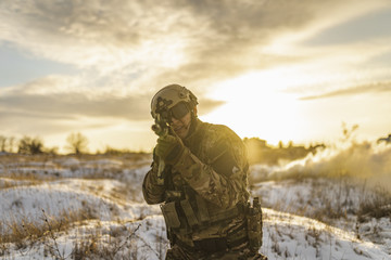 Modern war soldier army Man in camouflage in winter field stands and aiming. commandos with helmet...