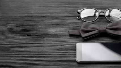 Stylish hipster fashion concept in minimal style. Trendy eyewear, bow tie black wooden grunge table