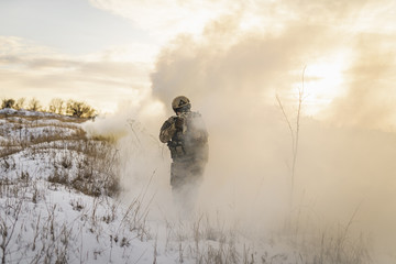 Soldier army man running through the smoke and explosions sun backlight and smoke background. modern warfare. atmosphere of battle. commandos on the winter battlefield in the smoke