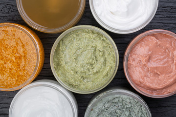 Set of cans of cream of various colors on black wooden background