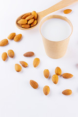 Almond milk with almond on white background. Homemade organic almond milk in a paper cup for healthy breakfast. Vegan milk from almonds nuts in kraft paper cup. Alternative milk. Zero waste
