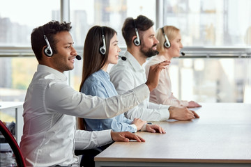 Obraz premium Indian black man spread right hand. Side view man with headset spread right hand in bright office.