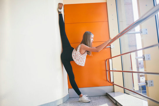 woman stretches throwing her leg on the wall