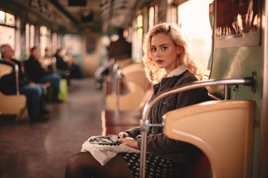 Young woman looking at camera while traveling in subway train