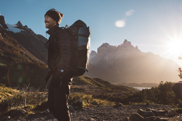 Happy backpacker standing in mountains in sunny day