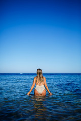 Girl in light swimsuit to bathe in the blue water of the red sea