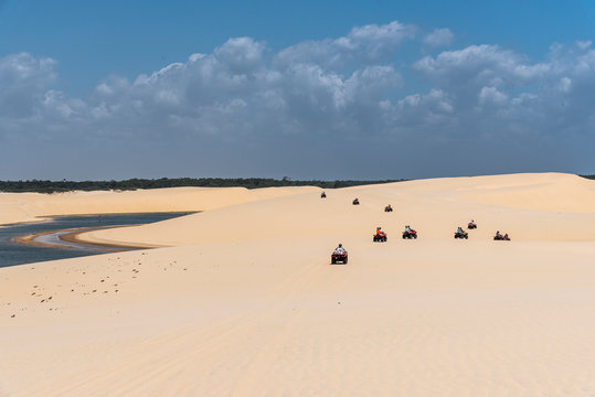 Group of friends riding quadricycles on white sand dunes and lagoons
