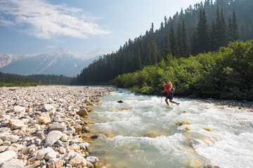 hiker crossing freezing river during backpacking trip.