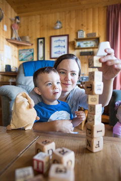Mother helps son build block tower.
