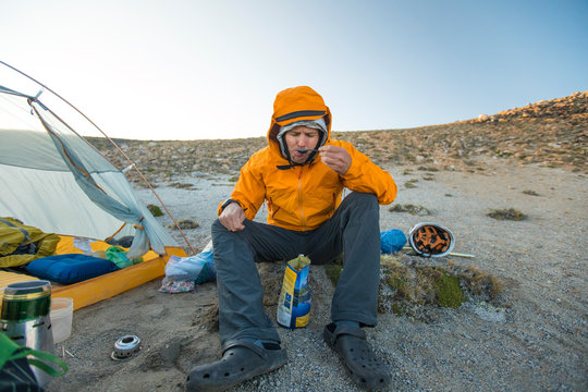 Hiker enjoys a meal next to his tent.