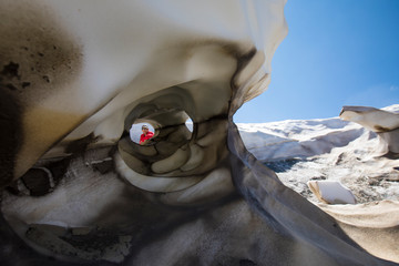 Portrait of hiker through hole in melting glacier.