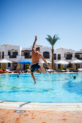 Naklejka premium Guy in shorts bathes in the pool under the bright sun