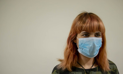 Girl with mask to protect her from Corona virus. Corona virus pandemic. Woman with mask with COVID 19 written.Beautiful girl with medical mask. People are hospitalized for prevention. Coronavirus.