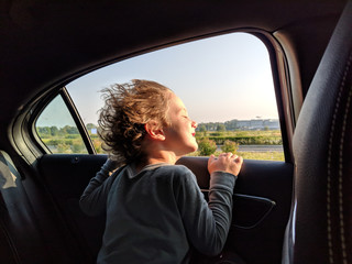 Boy leaning on window while traveling by car