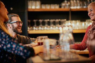 Bartender serving beer to customers. Pub interior.
