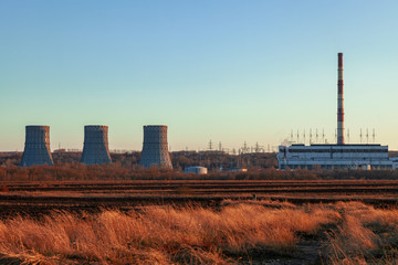 A distant thermal power plant illuminated by the rays of the setting sun.