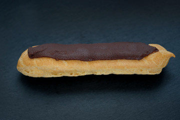 eclairs cake stuffed on a black background. homemade eclair covered with a strip of chocolate.