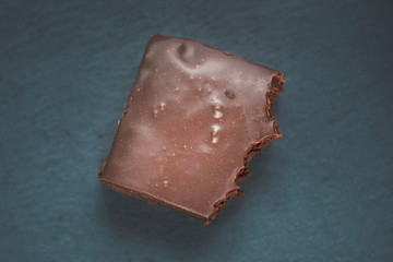 A bitten slice of chocolate brownie top view. Chocolate brownie on a black background. Delicious homemade chocolate dessert. Keep on a diet and lose weight.