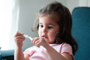 Adorable little baby girl is playing with pencil at home,sitting in a living room,happy childhood and domestic life concept