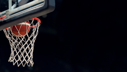 The orange basketball ball flies through the basket