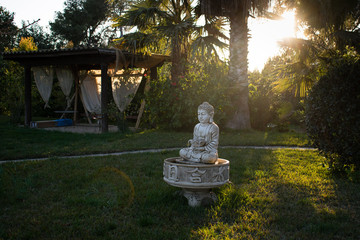 Stone buddha statue in the garden with palms, villa 