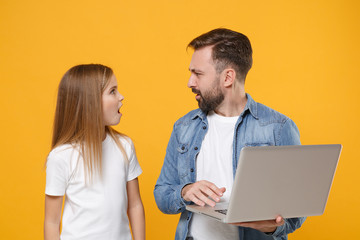 Fototapeta premium Shocked bearded man in casual clothes have fun with child baby girl. Father little kid daughter isolated on yellow background. Love family day parenthood childhood concept. Work on laptop pc computer.