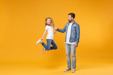 Smiling excited bearded man in casual clothes have fun with child baby girl. Father little kid daughter isolated on yellow background. Love family parenthood childhood concept. Holding hands jumping.